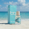 Perfume bottle and packaging labeled 'Beach Geeza' on a beach with ocean in the background